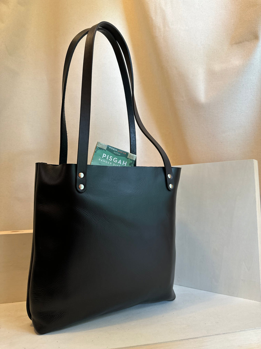 Our handmade Black Portfolio Leather Tote Bag is hand crafted in our Asheville, NC studio.   Made of the finest quality top grain Horween Chrome XL solid leather. It is our compact tote that can carry anything from top secret dossiers to mini bottles for apres-anything.  Made from the highest quality top grain, solid leather, this bag will outlast your sister's second and third marriages.  Black EDC Mini Leather Tote Bag