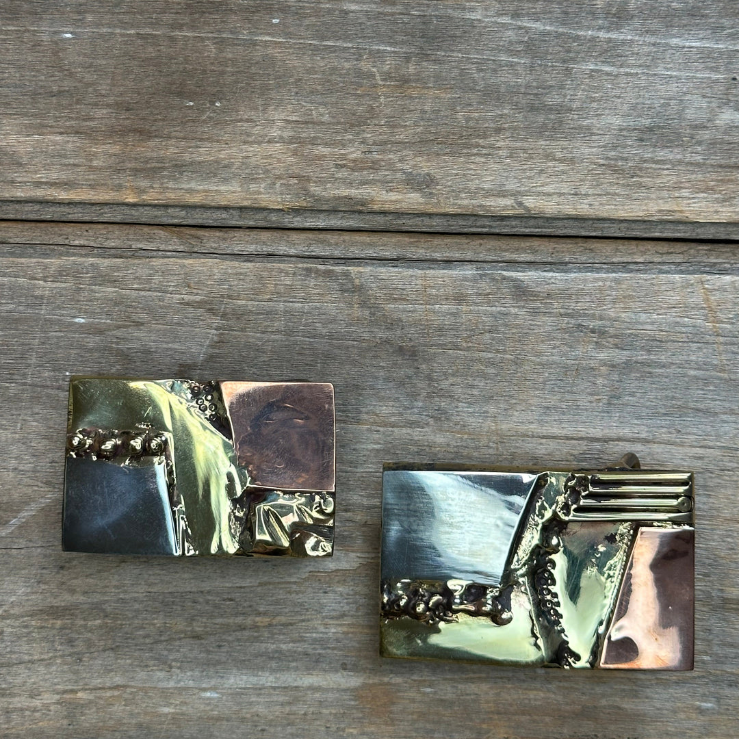 Two brass, copper, and nickel abstract belt buckles by David M. Bowman.  One fits an incah and a quarter belt and the other fits an inch and a half belt.  Each of these buckles is unique and handmade.