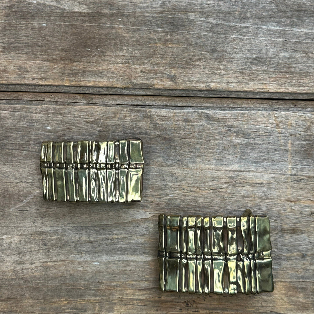 Two brass abstract "Spine" belt buckles by David M. Bowman. One is an inch and a quarter, one is inch and a half.
