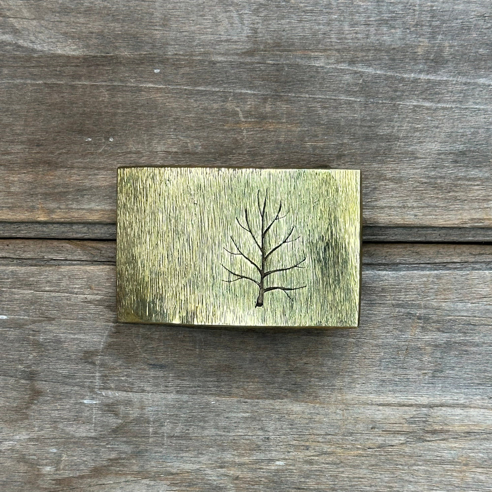 The "Tree" design by David M. Bowman is a timeless and durable design for those who wish to have a simple "go to" belt buckle to wear for any occasion.&nbsp; These belt buckles are handmade by David and his son Reed in their West Berkely, California studio.&nbsp; Each piece is handmade of solid brass and textured with a grinder, providing a durable glinting effect.