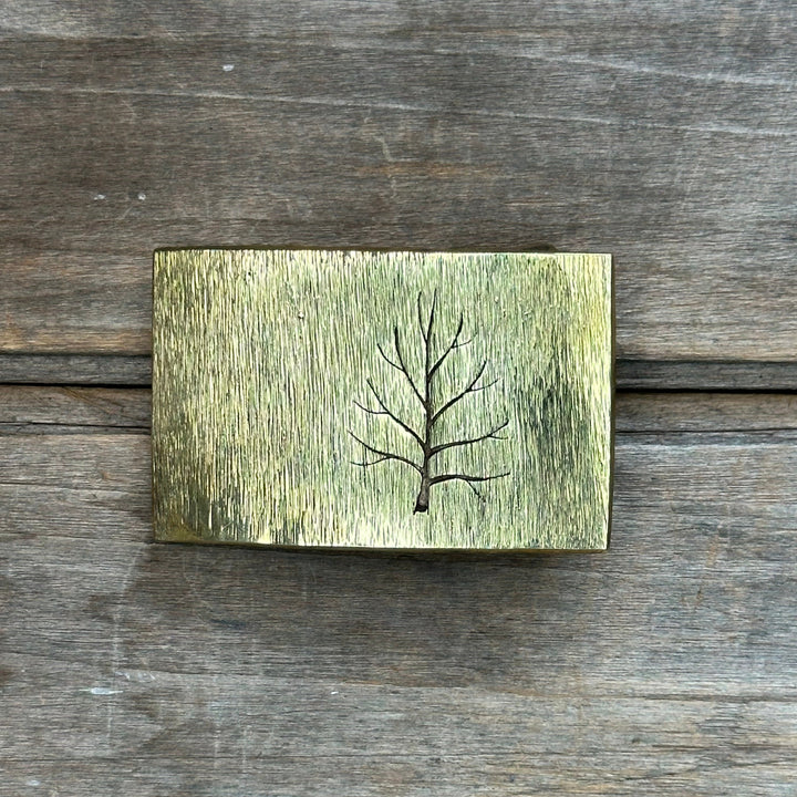 The "Tree" belt buckle by David M. Bowman is a timeless and durable design for those who wish to have a simple "go to" belt buckle to wear for any occasion.&nbsp; These belt buckles are handmade by David and his son Reed in their West Berkely, California studio.&nbsp; Each piece is handmade of solid brass and textured with a grinder, providing a durable glinting effect.