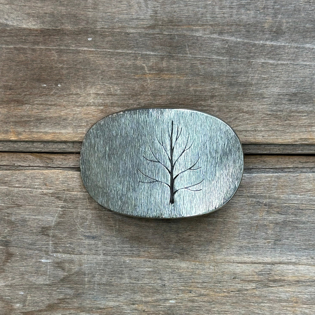 The "Tree" design by David M. Bowman is a timeless and durable design for those who wish to have a simple "go to" belt buckle to wear for any occasion.&nbsp; These belt buckles are handmade by David and his son Reed in their West Berkely, California studio.&nbsp; Each piece is handmade of solid nickel silver and textured with a grinder, providing a durable glinting effect.