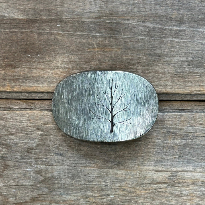 The "Tree" design by David M. Bowman is a timeless and durable design for those who wish to have a simple "go to" belt buckle to wear for any occasion.&nbsp; These belt buckles are handmade by David and his son Reed in their West Berkely, California studio.&nbsp; Each piece is handmade of solid nickel silver and textured with a grinder, providing a durable glinting effect.