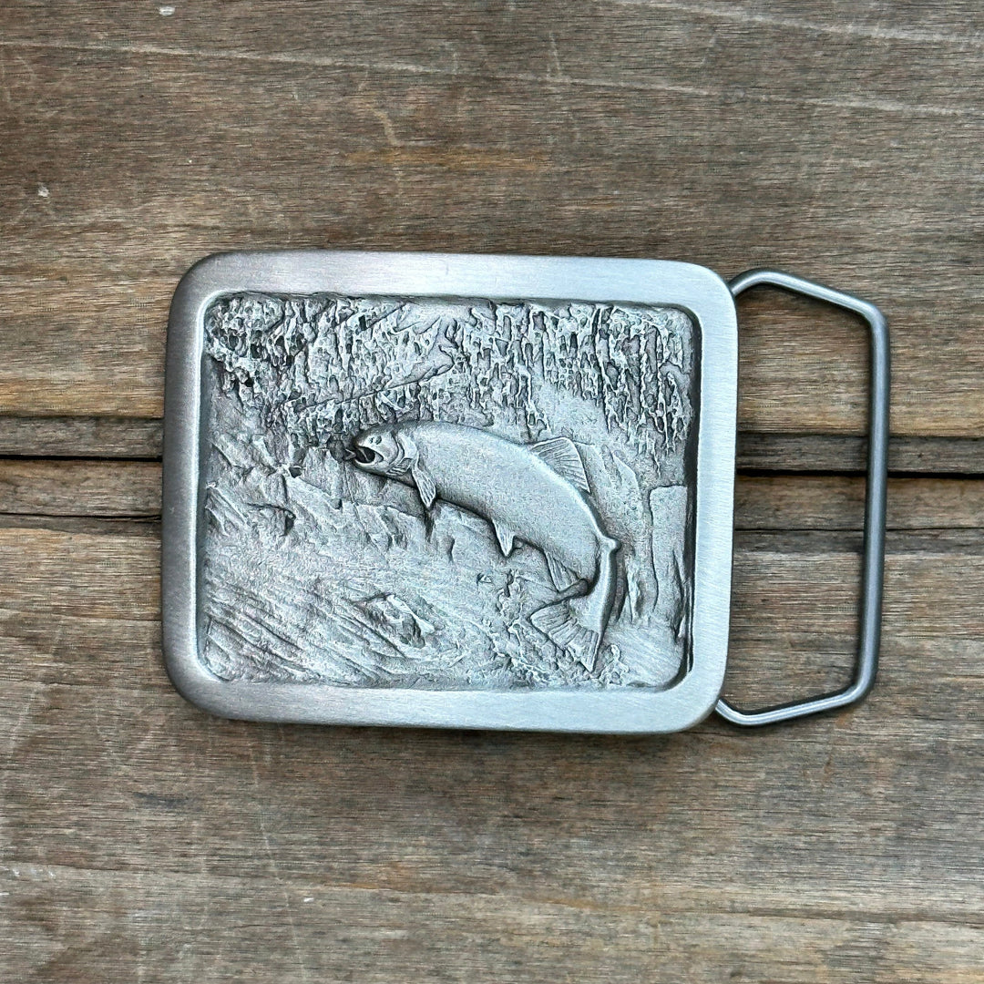 This is a pewter belt buckle with a silver tone.  It depicts a trout leaping upstream.