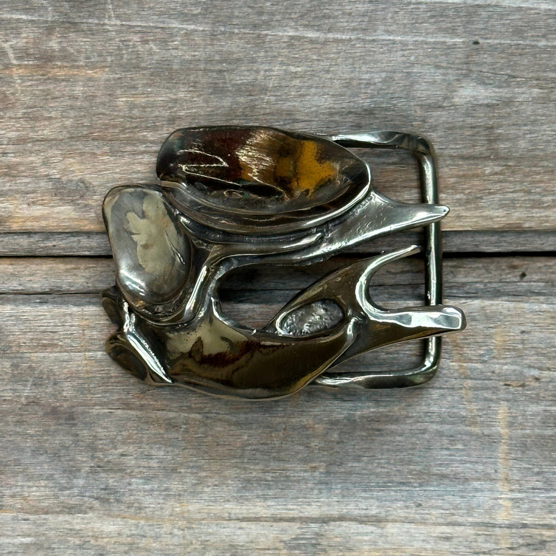 This is a brass belt buckle with a gold tone and high shine.  It is an abstract brutalist design by Andre van Bergeijk.