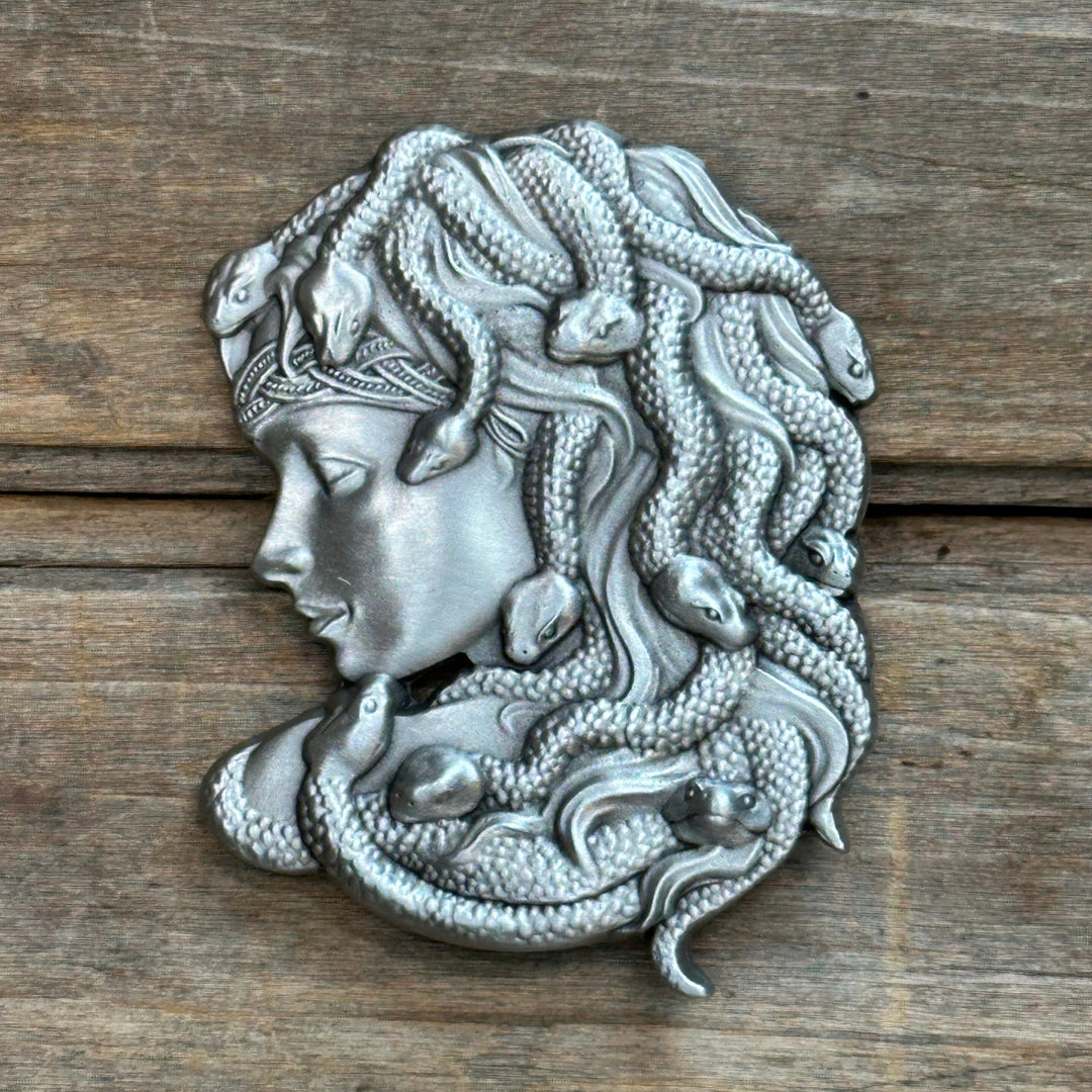 This is a pewter belt buckle with a sliver tone.  It depicts Medusa with snakes in her hair.
