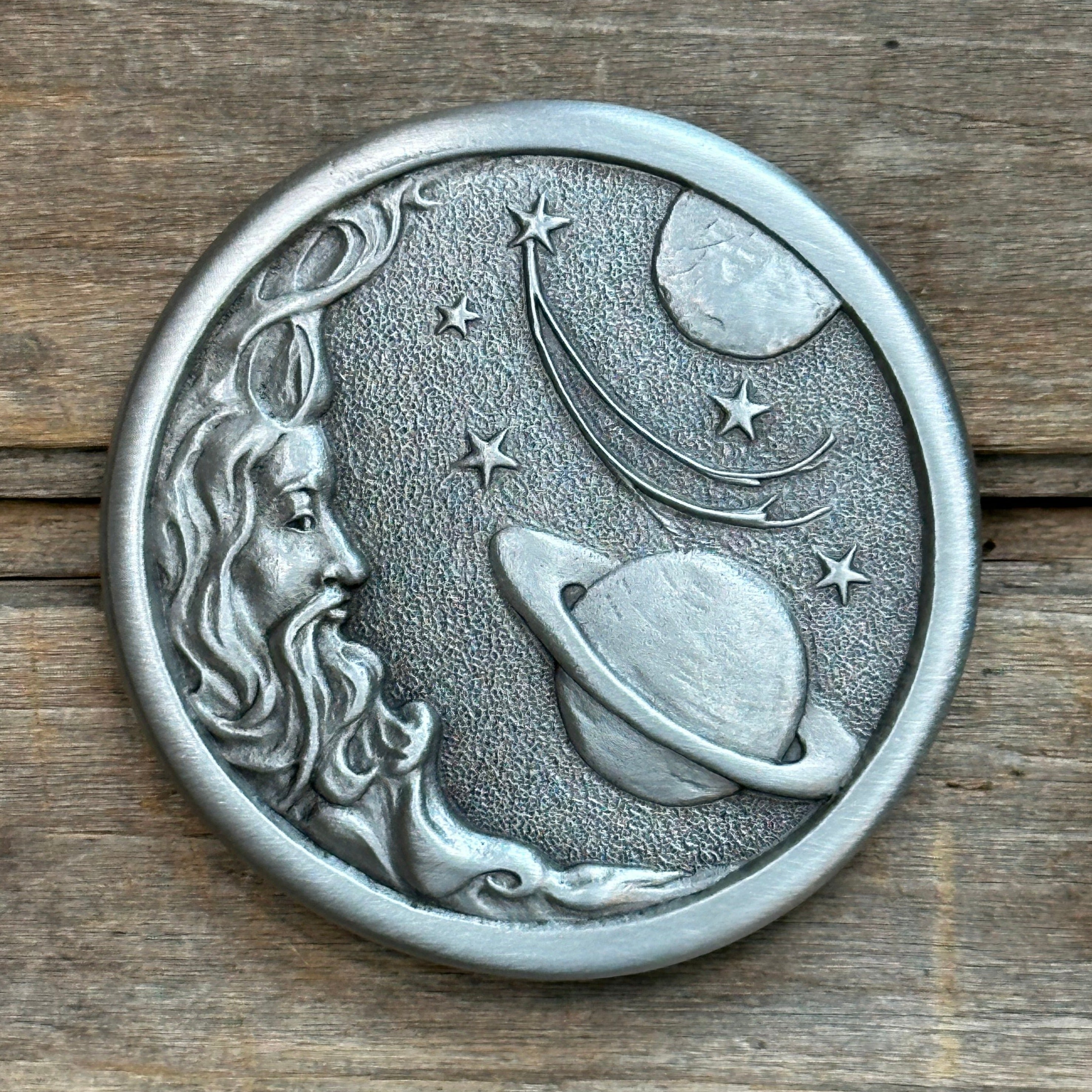 This is a pewter belt buckle with a sliver tone.  It depicts a man in the moon in a space scene with saturn, planet, and stars.