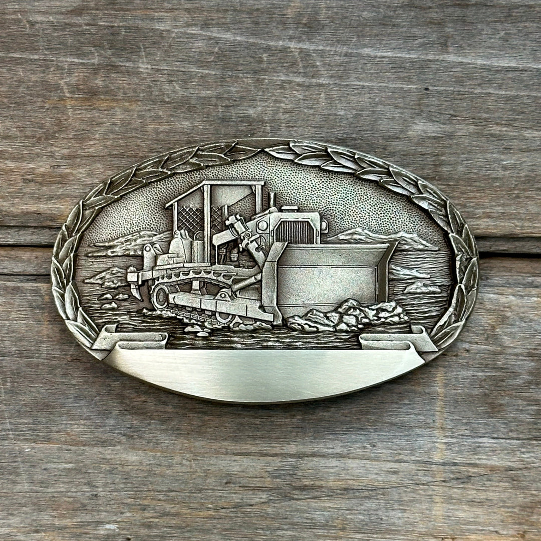 This is a solid belt buckle.  It depices a bulldozer moving dirt and earth with a leaf detail around the edge.