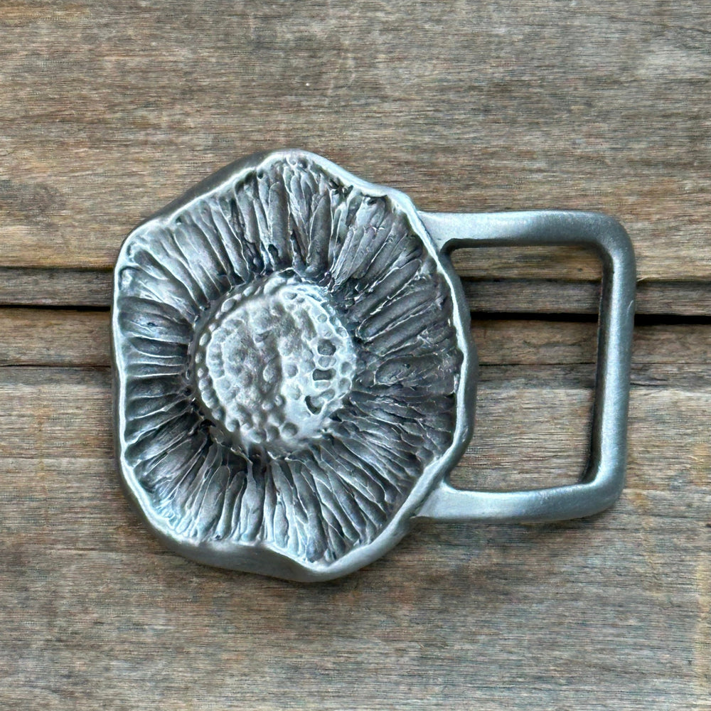 This is a pewter belt buckle with a sliver tone. it is a mushroom from below with the texture of the gills and stem.