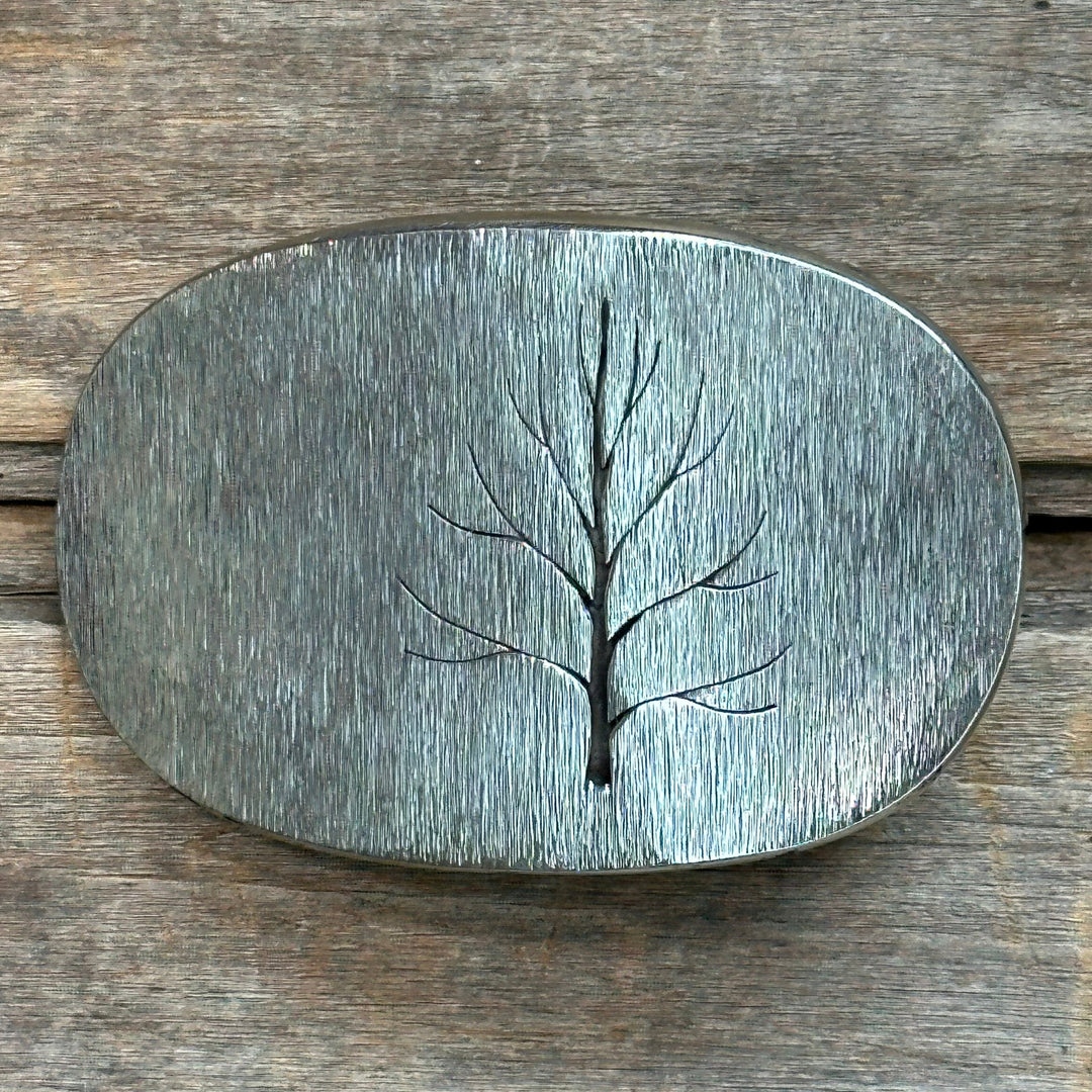 The "Tree" design by David M. Bowman is a timeless and durable design for those who wish to have a simple "go to" belt buckle to wear for any occasion.&nbsp; These belt buckles are handmade by David and his son Reed in their West Berkely, California studio. Each piece is handmade of solid nickel silver and textured with a grinder, providing a durable glinting effect.